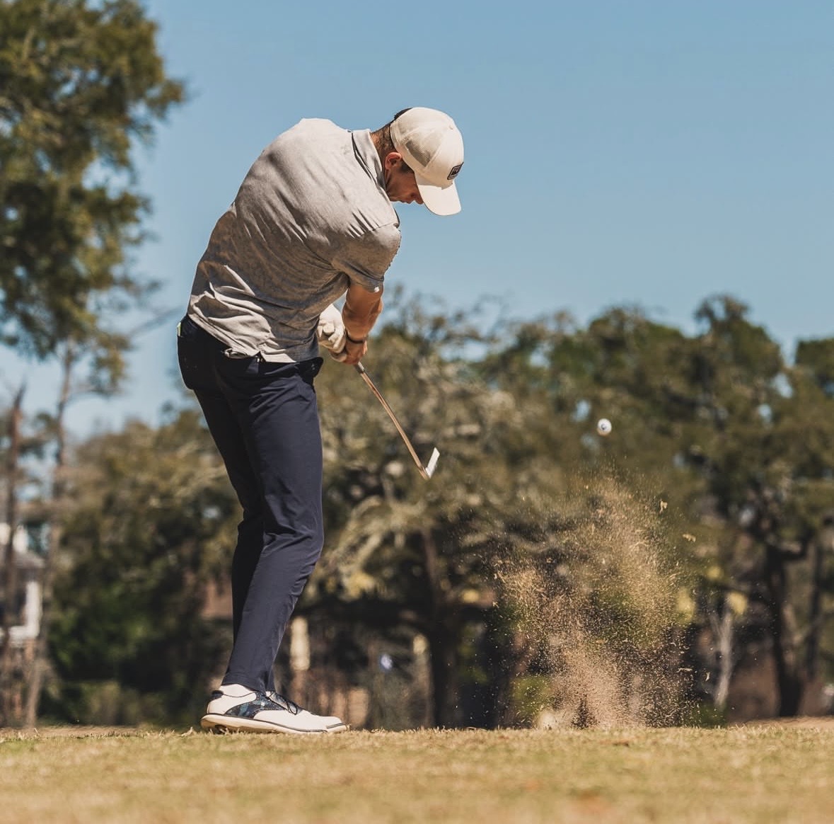 Thomas Taylor-Cross striking a bunker shot with a full sand splash